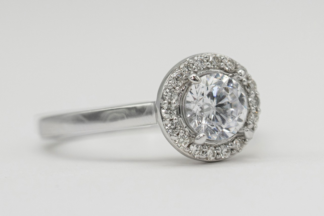 a silver toned engagement ring with a round cut center stone and halo setting