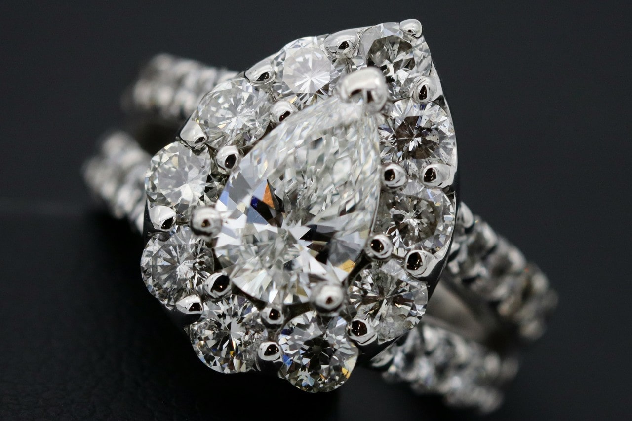 close up image of a pear shape engagement ring with a halo setting