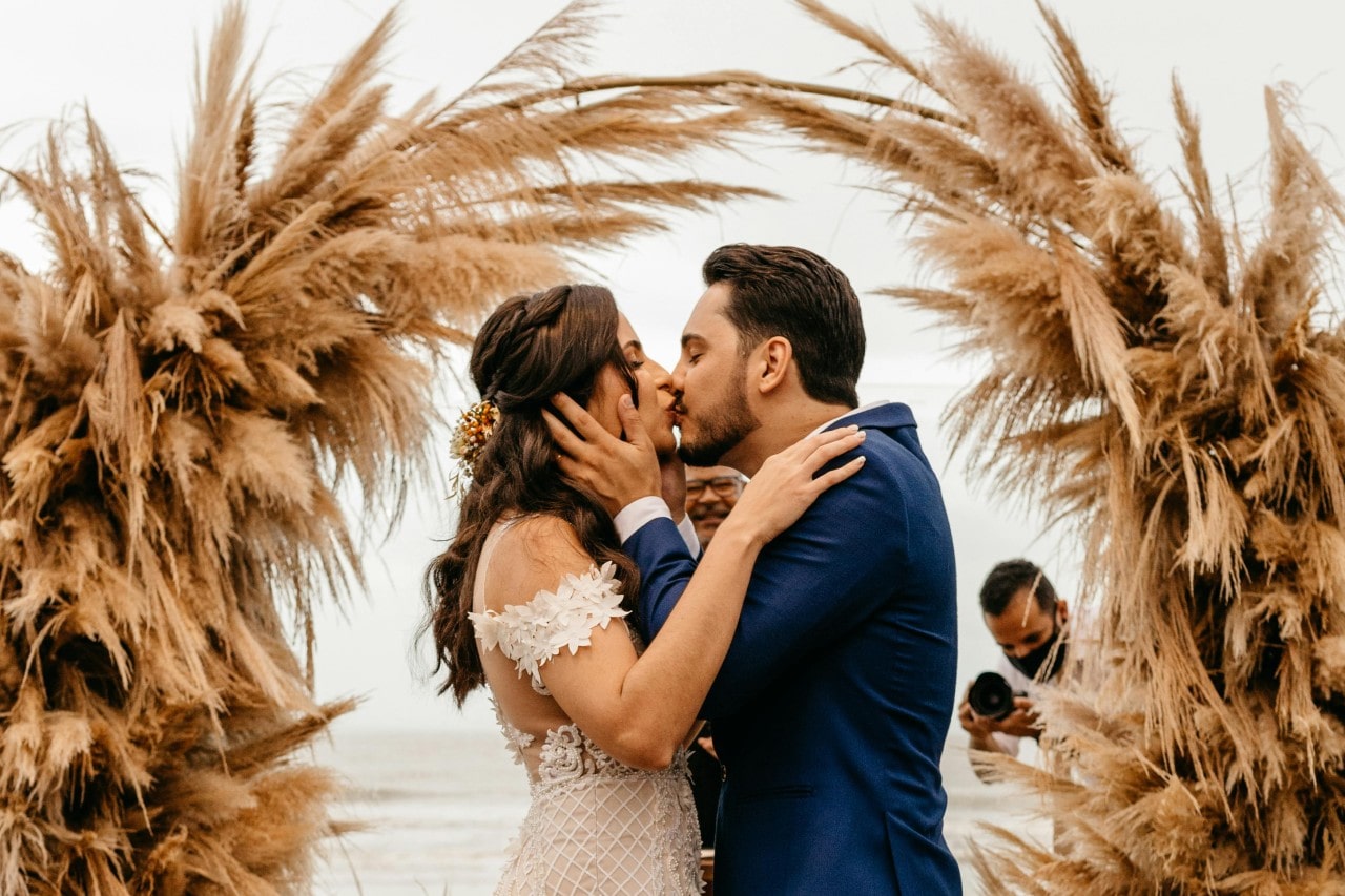 a bride and groom kissing at an altar on the beach