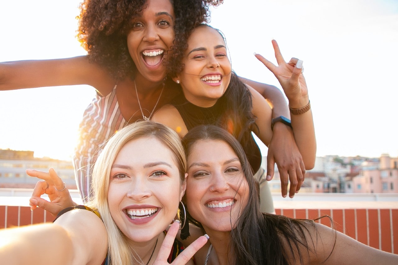 A bride-to-be and her bridesmaids taking a selfie in a waterside town.