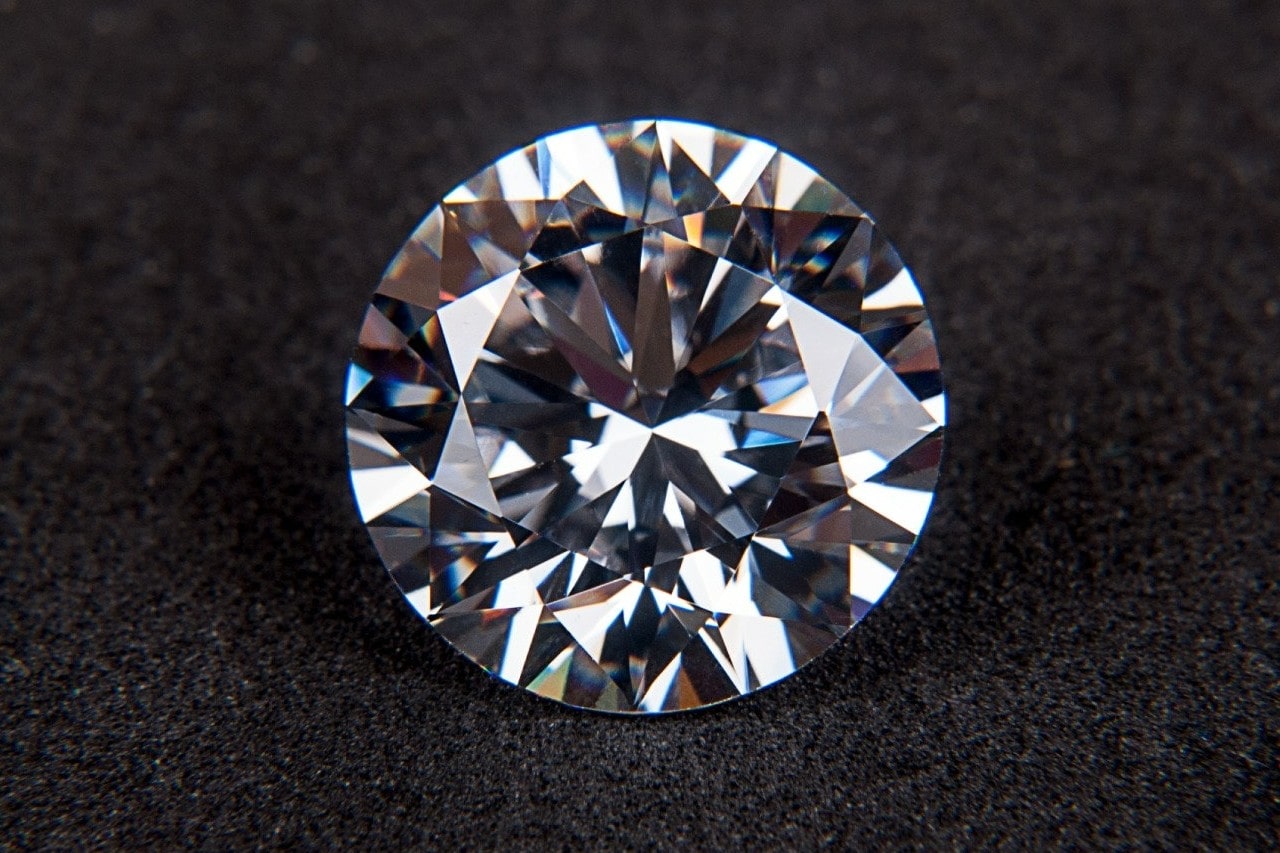 close up image of a round cut diamond on a dark, textured surface