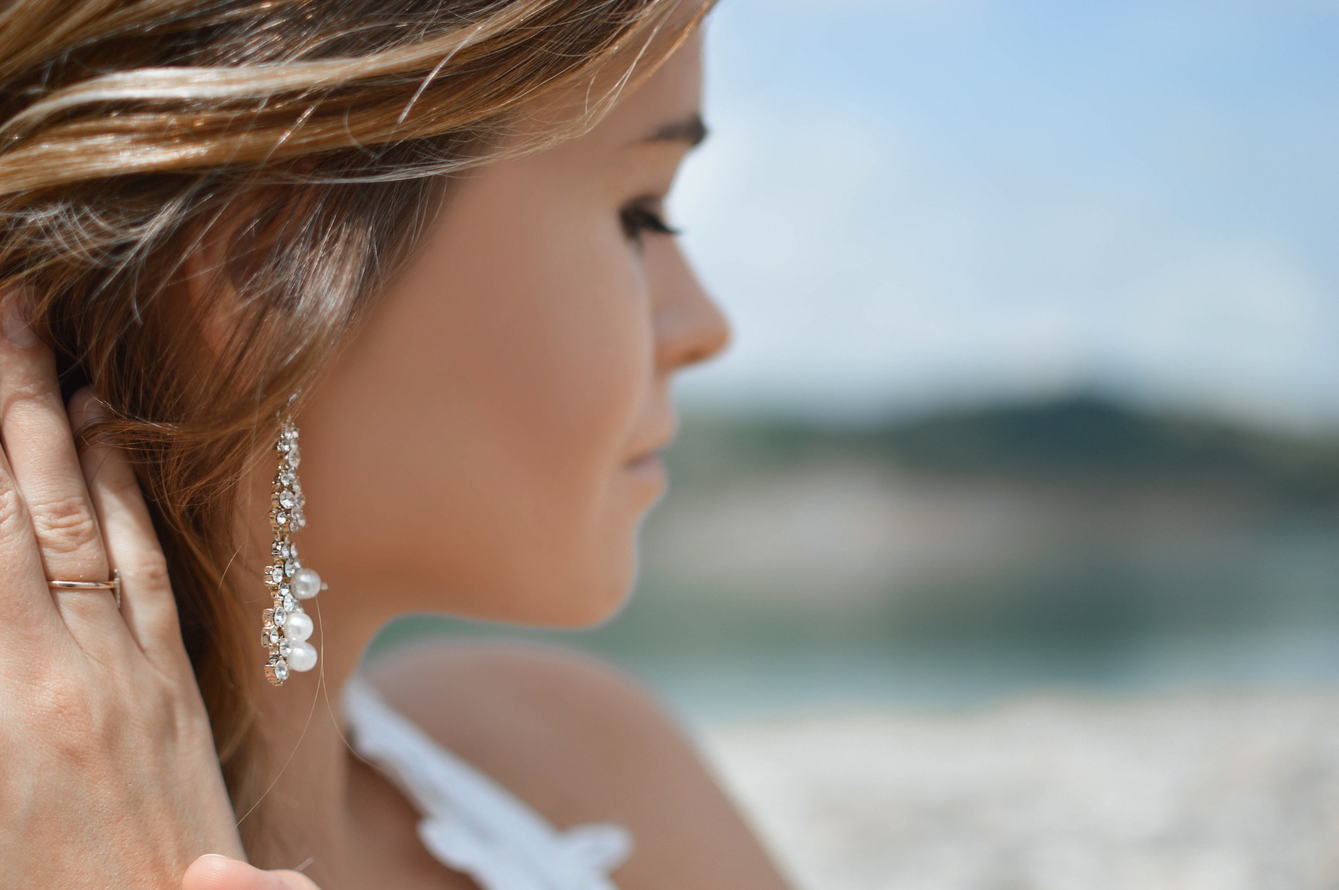 a woman looking away from the camera and wearing drop earrings with pearls and diamonds