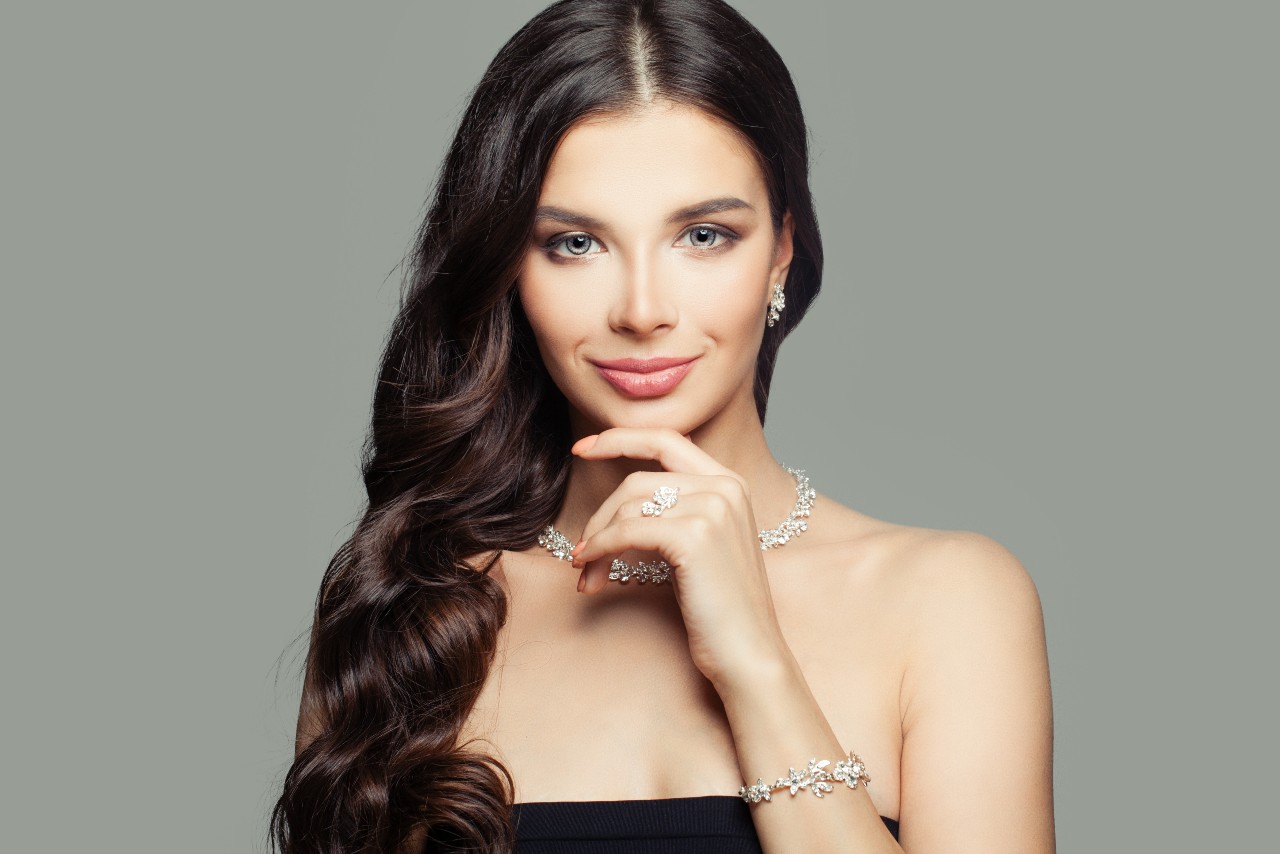 A woman in a strapless black top showcases a full set of matching floral diamond jewelry including earrings, necklace, bracelet, and ring. A woman in a strapless black top showcases a full set of matching floral diamond jewelry including earrings, necklace, bracelet, and ring.