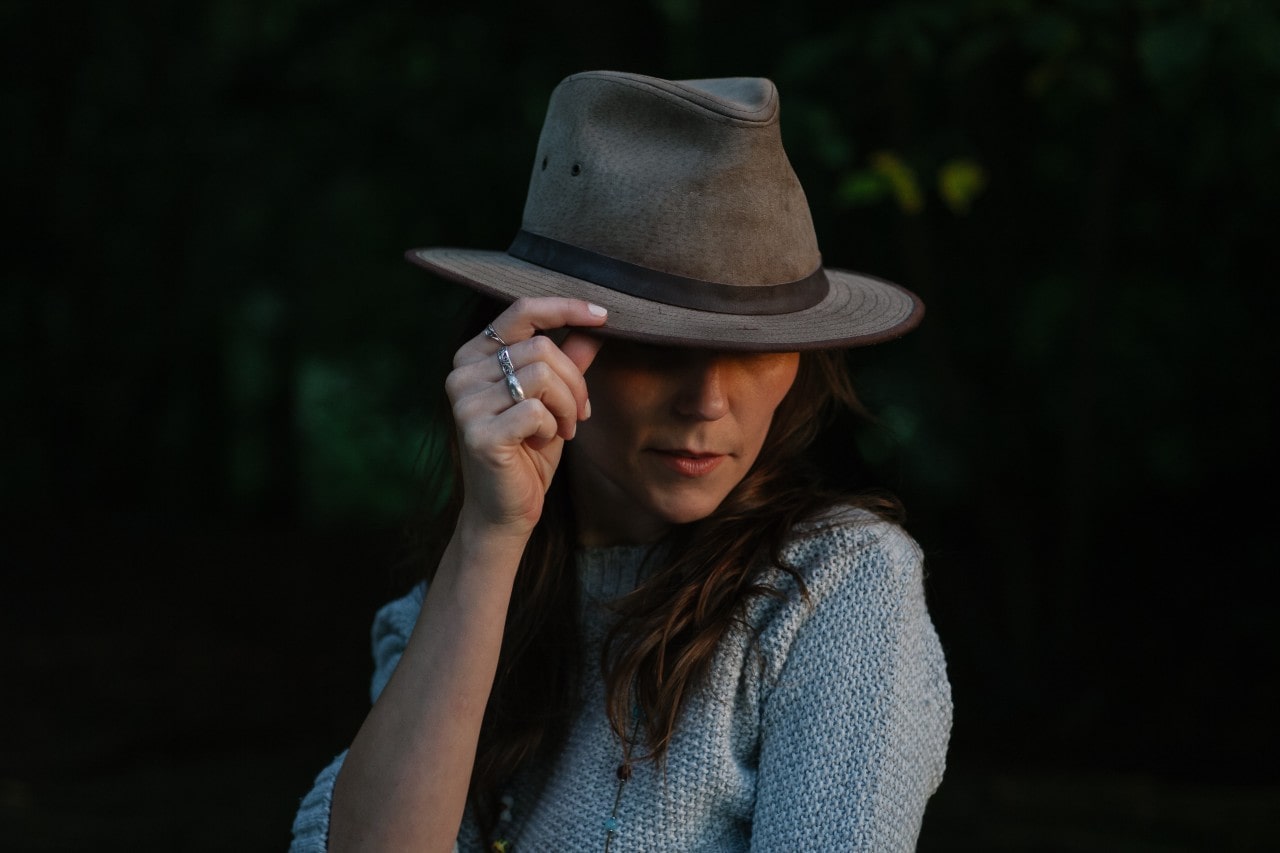 A woman in a fedora poses with three sterling silver rings on her hand.
