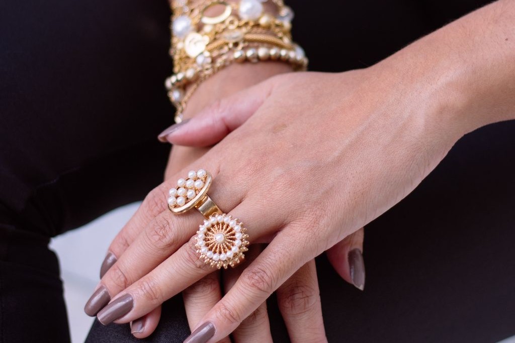 A woman wearing two pearl rings.