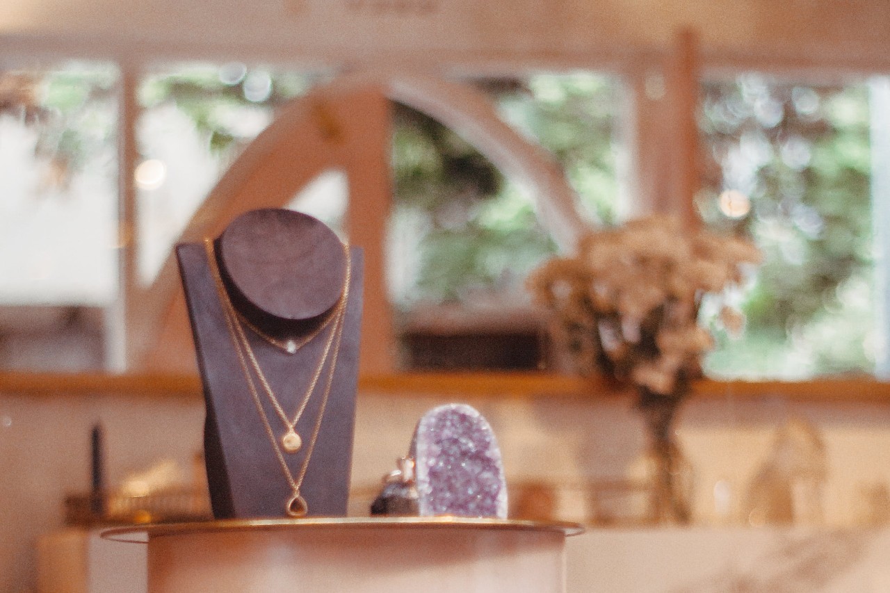 a necklace stand next to a purple crystal on a table in a jewelry store