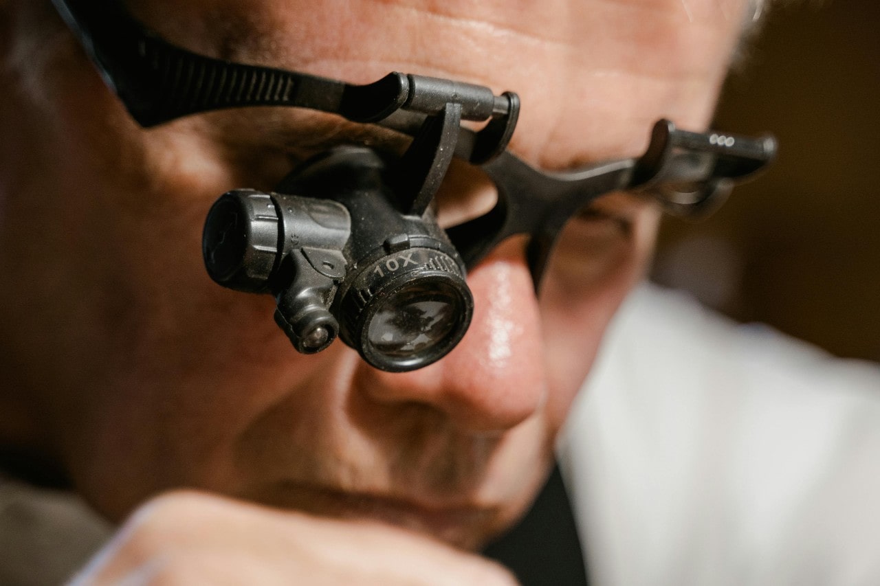 a jeweler looking through a magnifying glass, working on a project