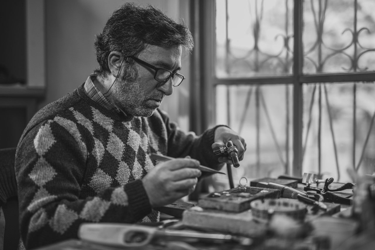 A black and white shot of a craftsman creating a custom piece of jewelry.