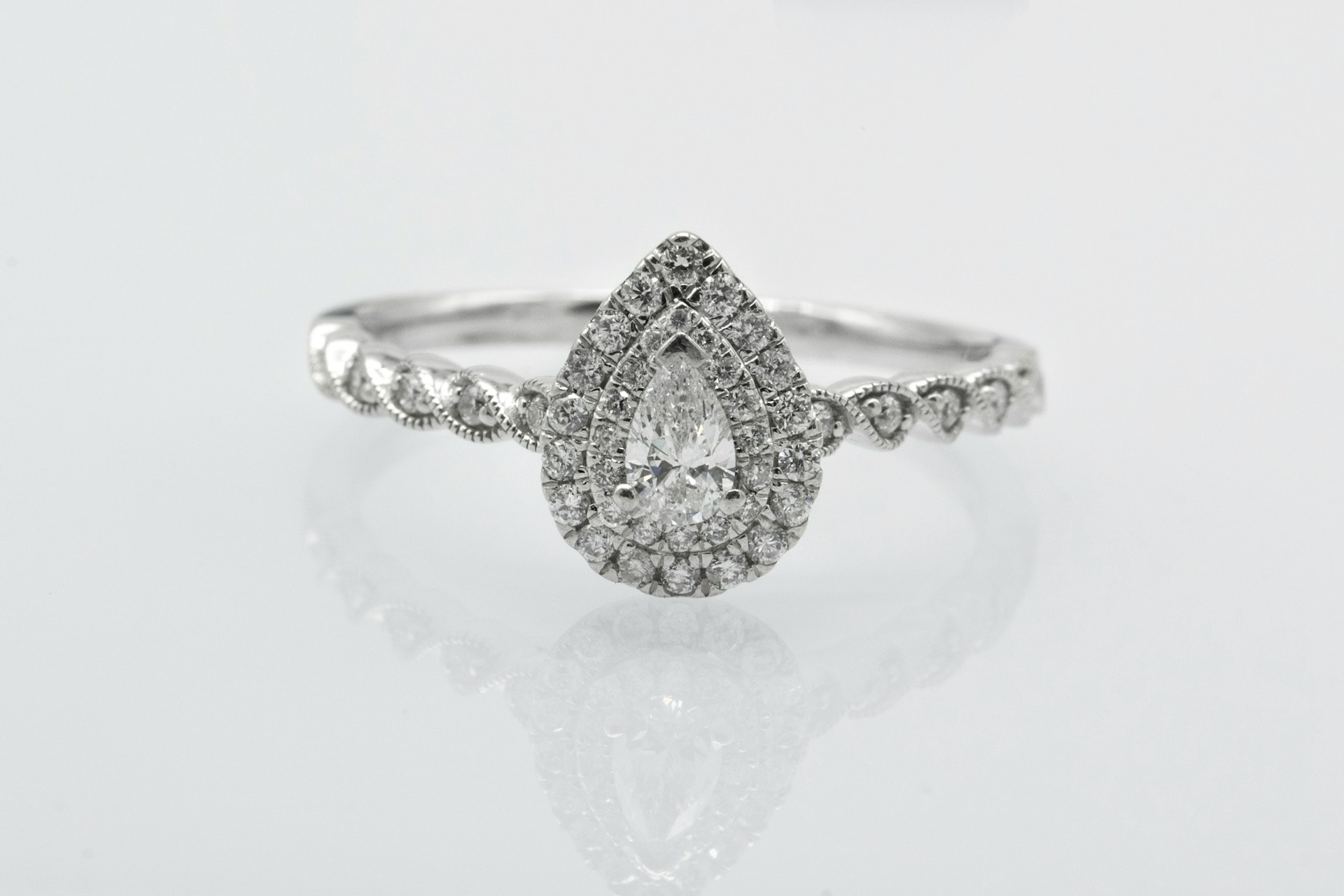 A white gold double halo engagement ring with a pear-shaped center stone.